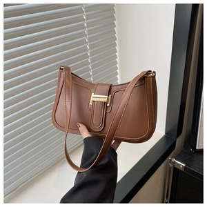 Close-up of caramel leather shoulder bag featuring minimalist gold buckle and smooth texture