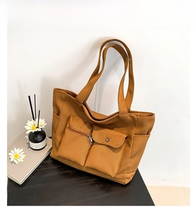 Detail of a brown large-capacity nylon tote bag with functional pockets and long straps