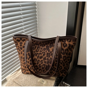 Détail du sac cabas léopard avec anses en cuir marron sur fond en tricot texturé