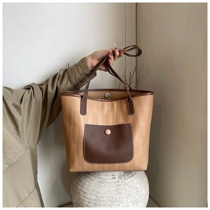 Detail of minimalist tote bag with khaki woven texture and brown leather front pocket