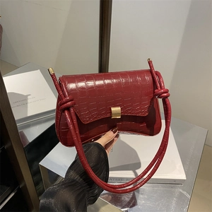 Elegant burgundy crocodile-patterned underarm bag with gold buckle and knotted strap details