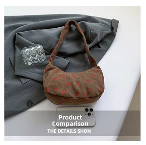 Detail view of brown corduroy crescent bag with strawberry prints and smartphone for scale