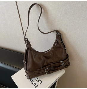 Detail of vintage brown motor bag showing shiny oil skin texture and silver buckle accents