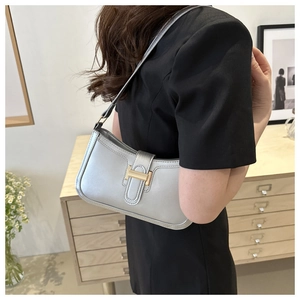 Silver baguette underarm bag featuring a textured finish and iconic gold H-shaped clasp