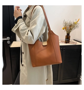 Close-up of brown leather tote bag featuring a gold magnetic clasp and vertical stitching