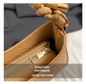 Detail of khaki woven leather texture and polished gold zipper hardware on underarm bag