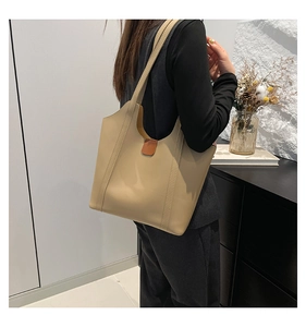 Minimalist beige leather tote bag for women worn by a model in a modern office setting