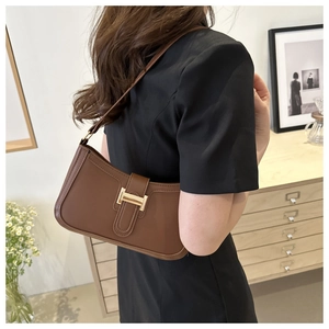 Detail of a dark brown faux leather underarm bag with a vintage gold metallic buckle