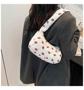 Detail of strawberry corduroy shoulder bag showing fabric texture and crescent shape