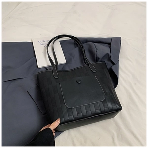 Detailed view of black PU leather tote with woven texture and a snap button front pocket