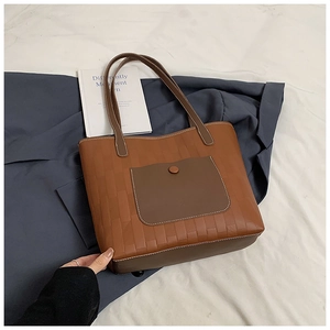 Close-up of brown woven tote bag featuring a front pocket and detailed stitching