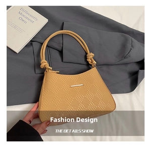 Close-up of camel woven texture handbag with unique knotted handle and gold metal trim