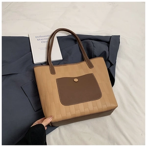 Detail of light brown tote bag with embossed woven texture and dark brown outer pocket