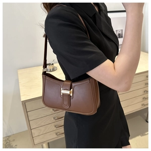 Brown vintage leather shoulder bag featuring a gold metal buckle worn by a model