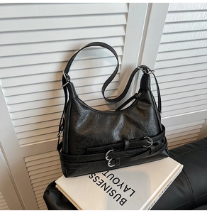 Detail view of black vintage motorcycle bag featuring glossy crinkled leather and silver D-rings