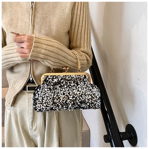 Détail d'un sac de soirée à paillettes avec poignée dorée et bandoulière en chaîne