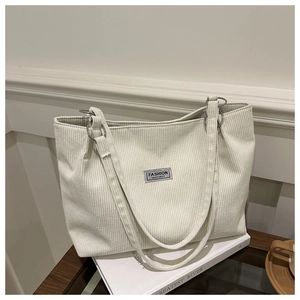 Detail of off-white corduroy tote bag showing metal ring connectors and fashion label