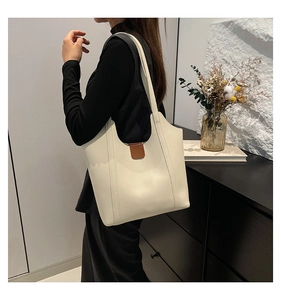 Detail of cream tote bag with vertical stitching and brown leather buckle strap