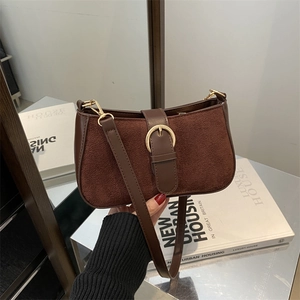 Vintage brown suede and leather shoulder bag with gold buckle on a marble background