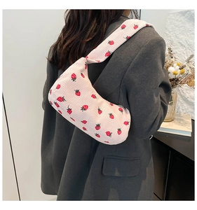 Pink corduroy crescent bag with red strawberry patterns shown on grey blazer