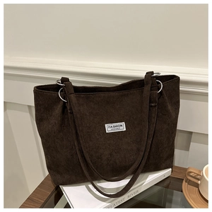 Detail of a brown corduroy tote bag with silver rings and a vintage fashion patch
