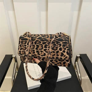 Chic leopard print shoulder bag with gold hardware held over a white book