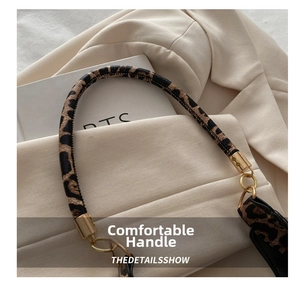 Detail of leopard print handbag handle with elegant gold hardware on beige background