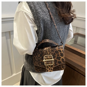 Sac à bandoulière tendance à motif léopard avec boucle dorée porté par un mannequin