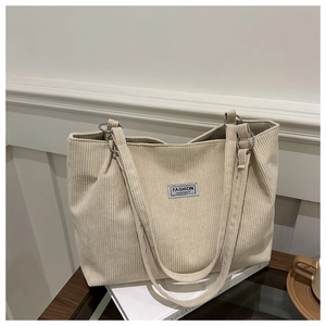 Detail of beige corduroy tote bag showing vertical texture and metal ring shoulder strap