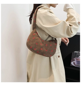 Detail of dark brown corduroy shoulder bag with strawberry pattern and soft texture