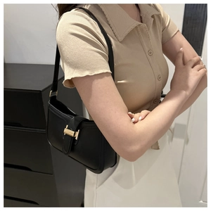 Close-up of black rectangular underarm bag with elegant gold metallic lock and buckle