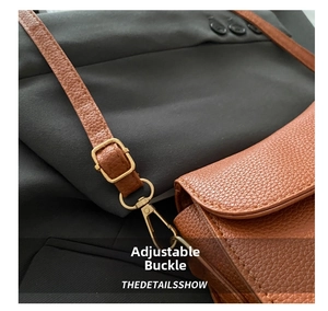 Detail view of brown pebbled leather shoulder strap with adjustable gold buckle hardware