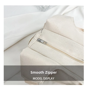 Detail view of smooth silver metal zipper on off-white textured nylon canvas tote bag