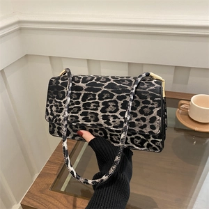 Minimalist leopard print underarm bag with gold hardware shown on a table