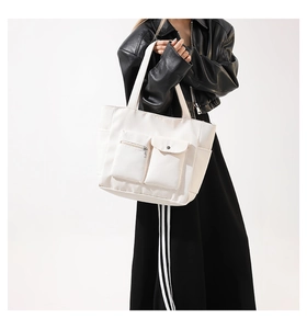 Detail view of white canvas tote bag with front zipper and flap pockets for daily commute
