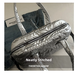 Detail der gesteppten silbernen Puffer-Handtasche mit Metallic-Finish und Reißverschluss