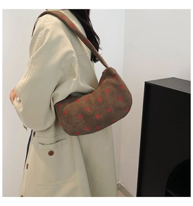 Detail of dark brown corduroy hobo bag featuring red strawberry embroidery on shoulder