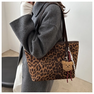 Détail d'un sac cabas léopard avec pendentif ours en peluche et bandoulière marron