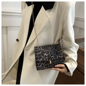 Detail of leopard print crossbody bag with gold chain strap and metal oval lock