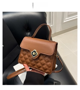 Detail of brown crossbody bag with quilted texture and gold four-petal flower lock