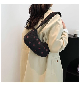 Detail of black corduroy crescent bag with pink strawberry embroidery on khaki trench coat