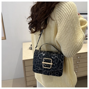 Détail du sac à bandoulière léopard avec boucle dorée sur un mannequin vêtu de beige