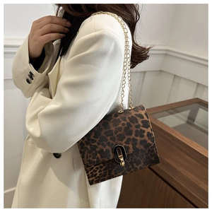 Detail of leopard print crossbody bag with gold chain strap on a white blazer