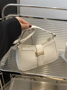 Minimalist white leather shoulder bag with gold buckle shown in a stylish hand-held pose