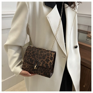 Detail of leopard print crossbody bag with gold chain strap and metal clasp on white coat