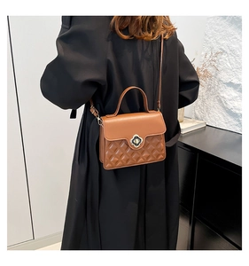 Brown leather crossbody bag with quilted diamond pattern and clover-shaped metal clasp