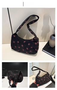 Close-up of black corduroy shoulder bag featuring pink embroidered strawberry patterns