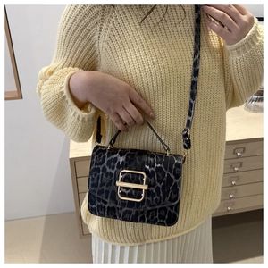 Détail du sac léopard avec boucle dorée porté sur un pull en maille beige élégant