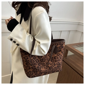 Détail du sac cabas léopard avec anses en cuir marron porté par un mannequin femme