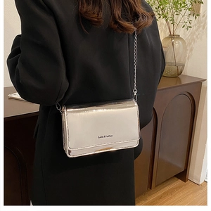 Silver mirror crossbody bag with chain strap shown on model in modern indoor setting